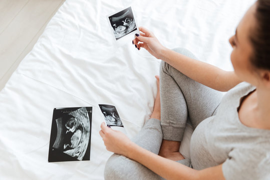 Closeup of pregnant woman sitting and looking at ultrasound photos