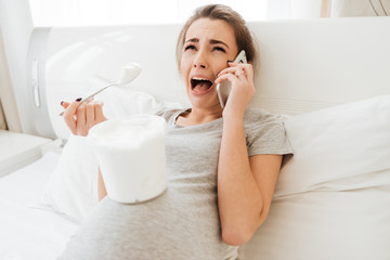 Upset frustrated pregnant woman crying and talking on cell phone