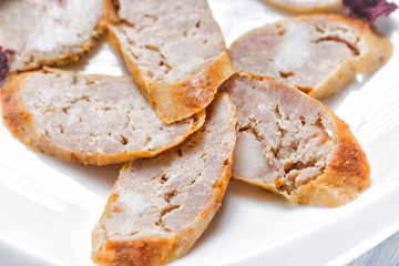 Sliced pieces of meat sausage on white plate. Close up with selective focus