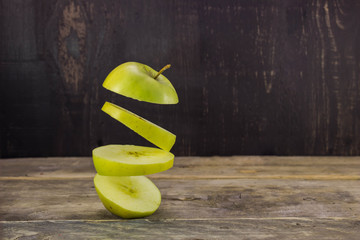 Sliced apple floats in the air on rustic wooden table