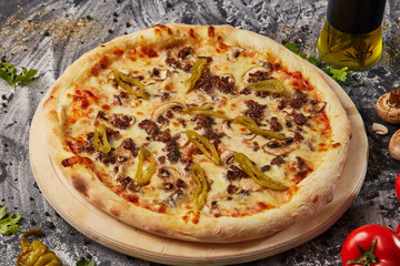 whole italian pizza on wood table with ingredients in black table