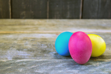 Three colorful easter eggs on wooden table . Happy Easter