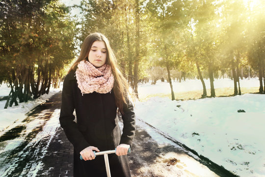 teen girl in black coat and long brown hair with schooter