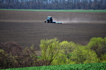 Spring agricultural panoramic scenery with fields, tractor, winter wheat and fresh herbs