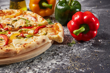 whole italian pizza on wood table with ingredients in black table