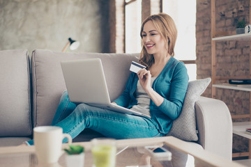 Concept of online shopping and payment.  Portrait of young smiling woman sitting on a sofa at home,...
