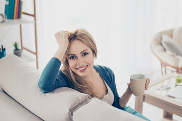 Young pretty cute woman enjoying coffee in the morning sitting on the sofa