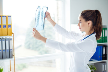 Doc at her medical office standing against window and looking at x-ray picture