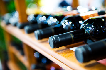 Group of red wine bottles stacked on wooden racks.