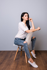 Beautiful young woman posing and leaning on chair's back