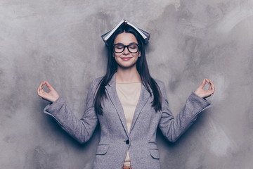 Portrait of glad relaxed young woman in suit and glasses close eyes and holding hands in om...