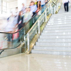 Obraz premium Group of businesspeople moving down on escalator in office. blurred motion.
