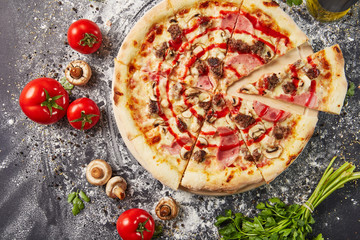 whole italian pizza on wood table with ingredients in black table