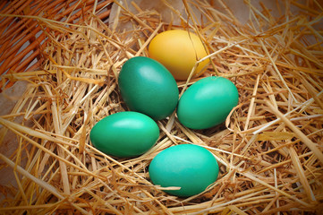 Colorful Easter egg decorations on natural straw and wood. Overhead view.