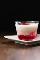 Strawberry flavored tapioca pudding in glass cup on dark wood table and black background
