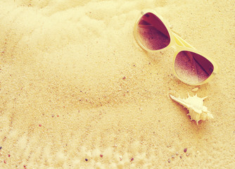 Fototapeta na wymiar Seashells and sunglasses on sand, top view, toning. Sea summer vacation background with space for the text
