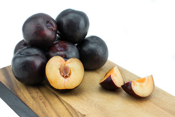Ripe tasty plums on the wooden board, isolated on white background with clipping path