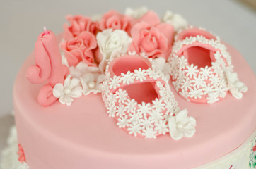Beautiful pink cake for the birthday girl, close-up. Princess shoes on the cake