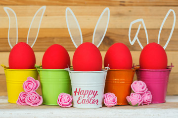 red Easter eggs with Rabbit ears in colored buckets, selective focus image, Card Happy Easter 