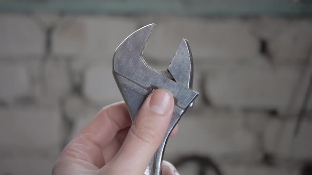 Brilliant adjustable spanner and  male hands in work.  
