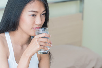 Beautiful woman holding a glass of water to drink in bed.