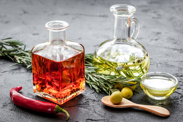 oil in carafe with spices, olives and chili on stone background