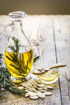 oil in carafe with pepitas and rosemary on wooden background