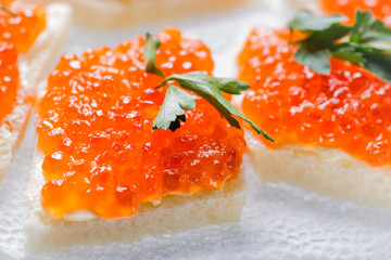Sandwiches with salmon red caviar and herbs on white napkin. Close up image with selective focus