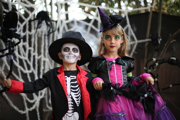 Trick-or-treating kids on Halloween patch. Boy in a Halloween costume of skeleton with hat and smocking and a girl with witch costume.