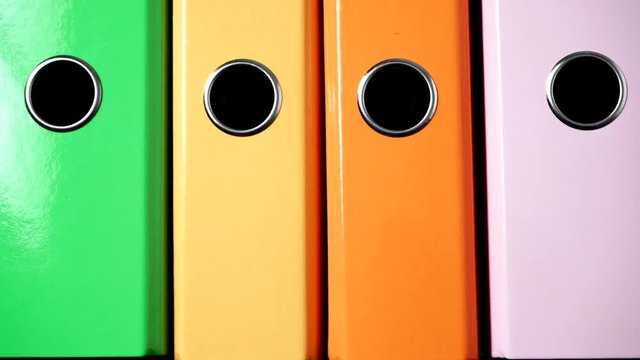 Close up of many colorful file folders, ring binders as vivid color office background. Dolly slider shot 4K ProRes HQ codec