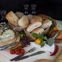 Selection of buffet food, bread, wine, fruit and cheeses.