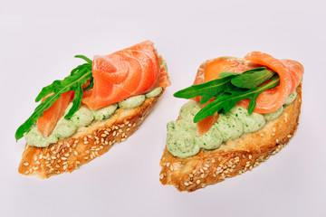 Two bruschettes with arugula in fillet of tuna and green sauce