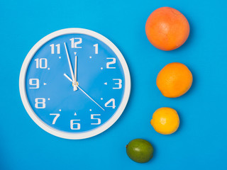 orange or citrus fruit with vitamin for healthy diet and clock isolated on blue textured background