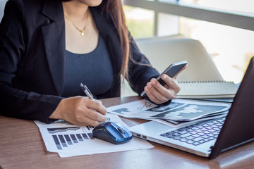 Close Up businessmen working at a coffee shop with a document with a smartphone and a laptop computer.
