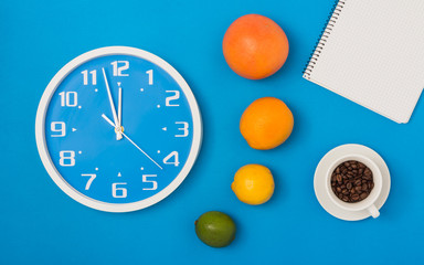 orange or citrus fruit with vitamin for healthy diet and clock isolated on blue textured background. Coffee cup with roasted beans. Place to your text