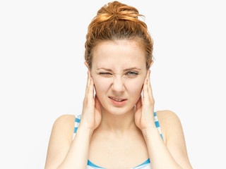 Young woman with red hair closing her ears with her hands on white background