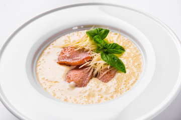 Cream soup with basil, meat steak and cheese on plate.