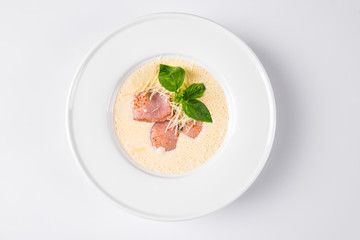 Cream soup with basil, meat steak and cheese on plate.