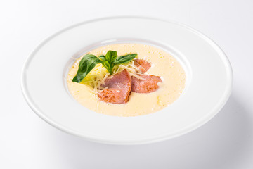 Cream soup with basil, meat steak and cheese on plate.