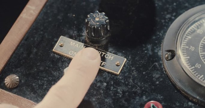 Hand operating old electrical equipment with dials and switches