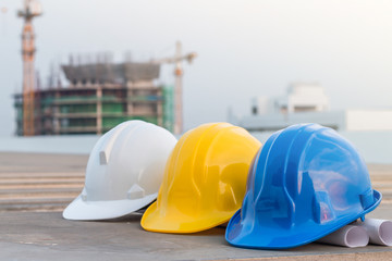 The safety helmet and the blueprint at construction site with crane background