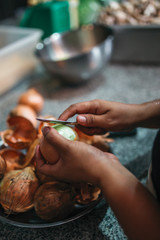 Close up of woman hands peelling the onion, preparation for cooking
