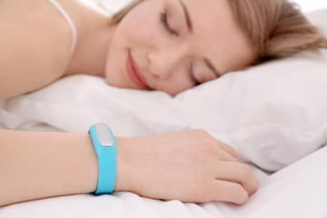 Obraz na płótnie Canvas Young woman with sleep tracker resting in bed at home
