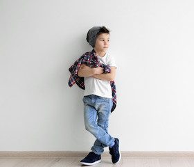 Cute stylish boy near light wall