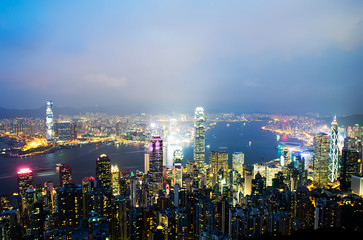 Hong Kong cityscape at night with victoria harbour and large group of tall buildings.