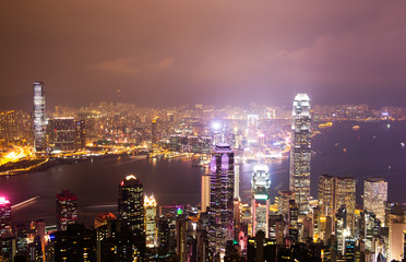 Hong Kong cityscape at night with victoria harbour and large group of tall buildings.