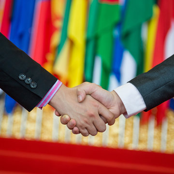 Businessmen shaking hands in front of the multi - national flag.    international business