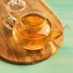 Teapot full of tea on teal texture with copyspace