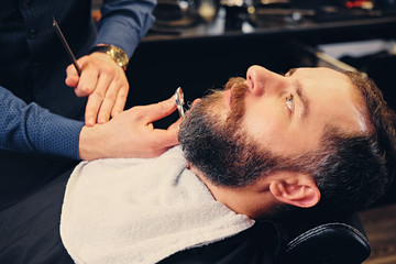 Obraz na płótnie Canvas Close up image of barber makes beard cut of a man.