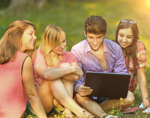 a group of students with laptop relaxing in the Park on Sunny day